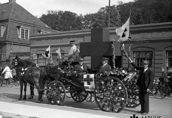 Røde Kors optog foran redningskorpset Zonen i Aarhus 1938. Bemærk det kæmpestore røde kors på vognen og hestenes seletøj. Foto: Aarhus Arkivet.